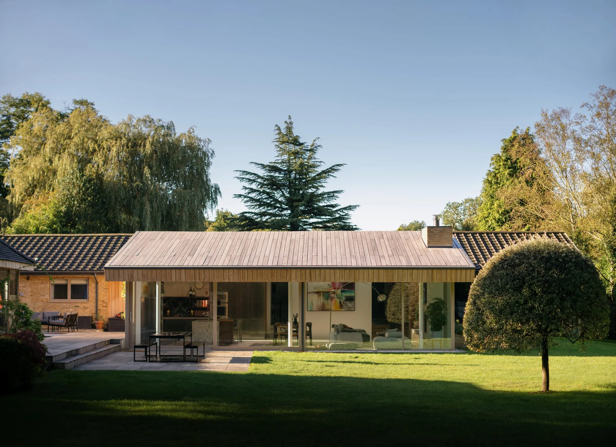 A 1960s bungalow in Woking, extended with a long glazed garden room across a lawn