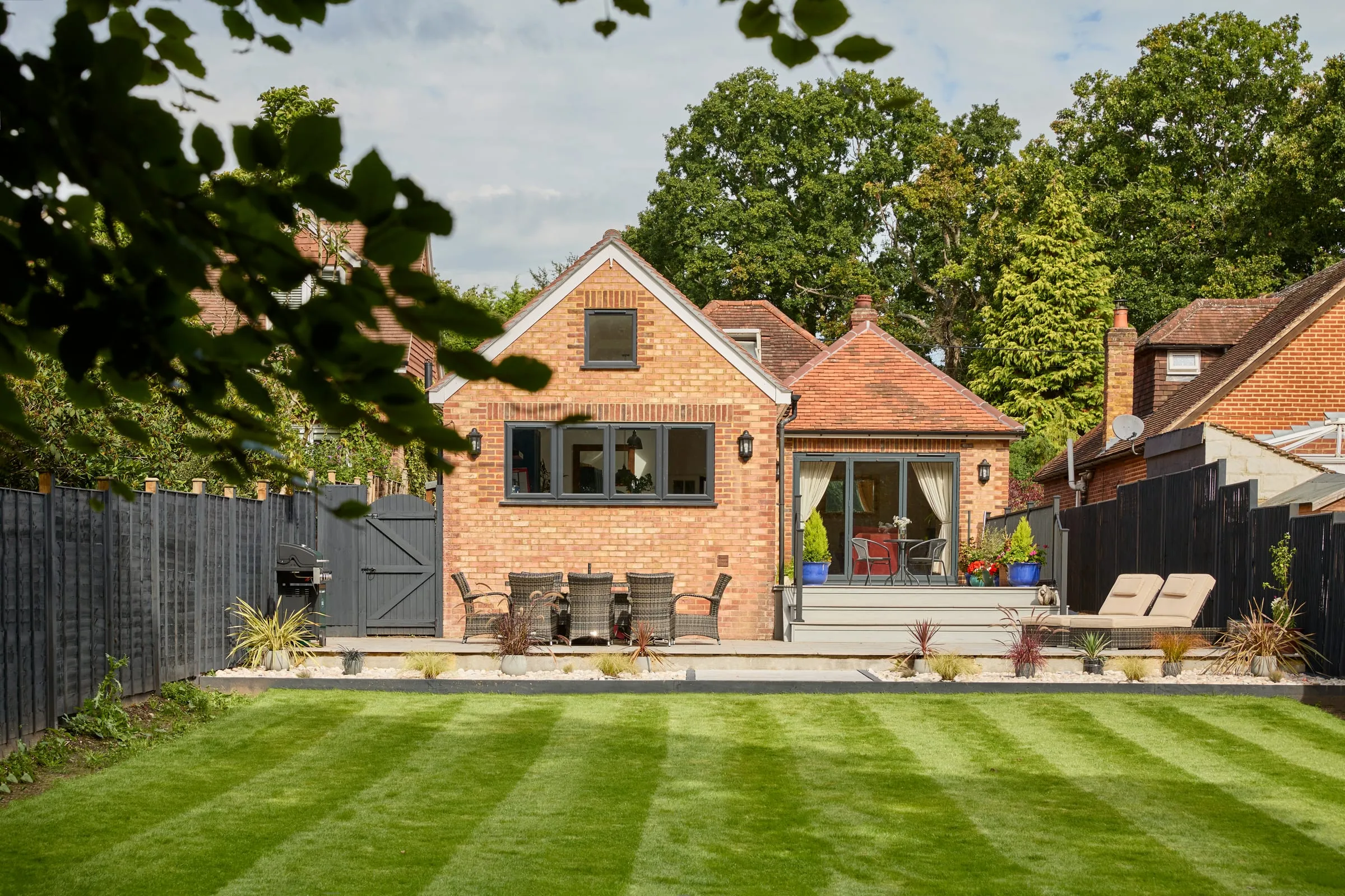 The rear of the renovated Chobham bungalow, with its new extension opening onto the lawn