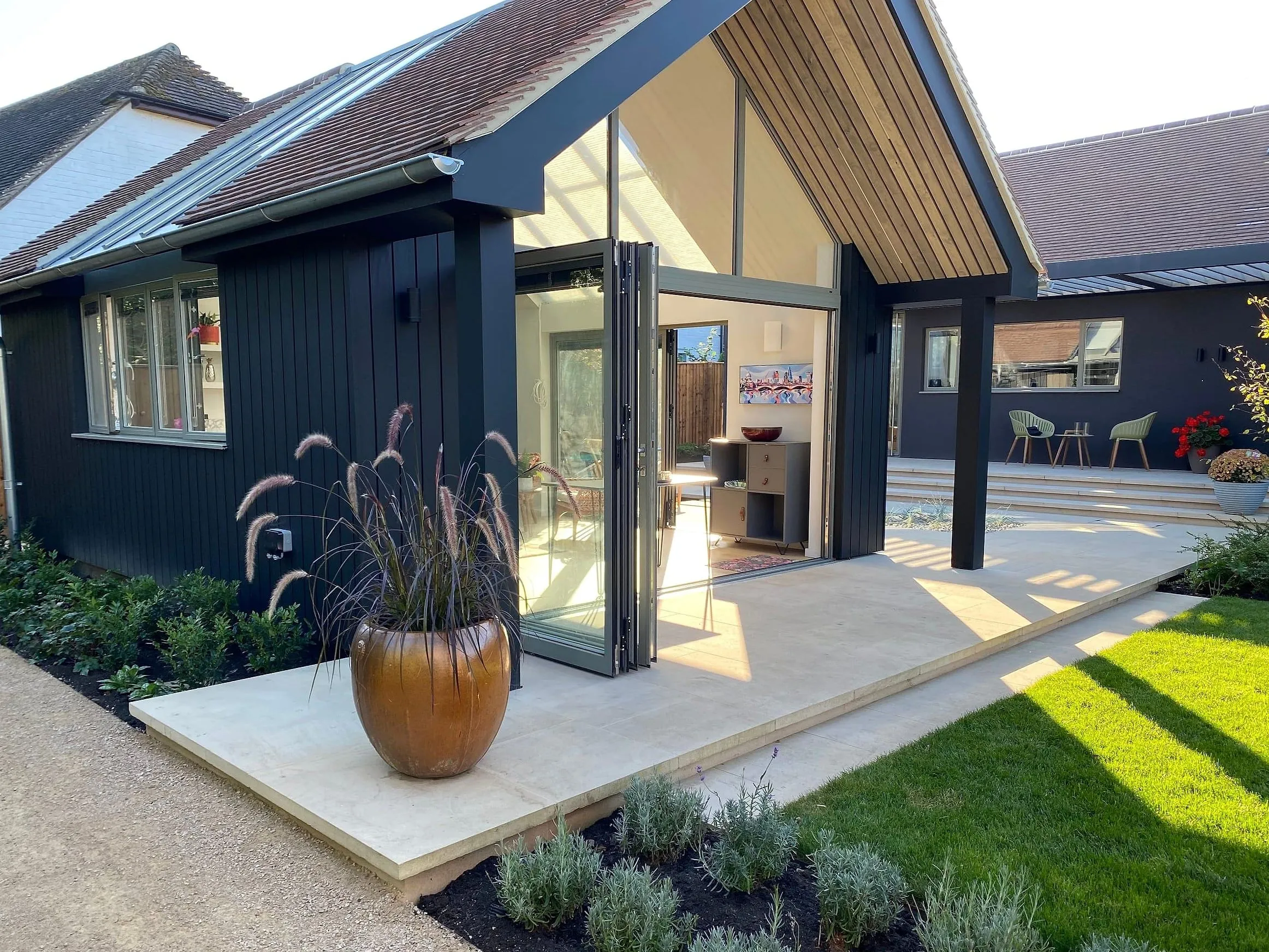 The garden room from the lawn, its glazed gable and black timber cladding catching the afternoon sun