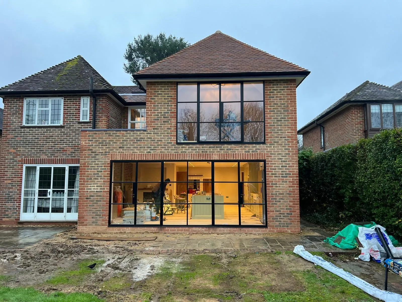 The rear of a Farnham house during building work, with a new two-storey extension and steel-framed glazing