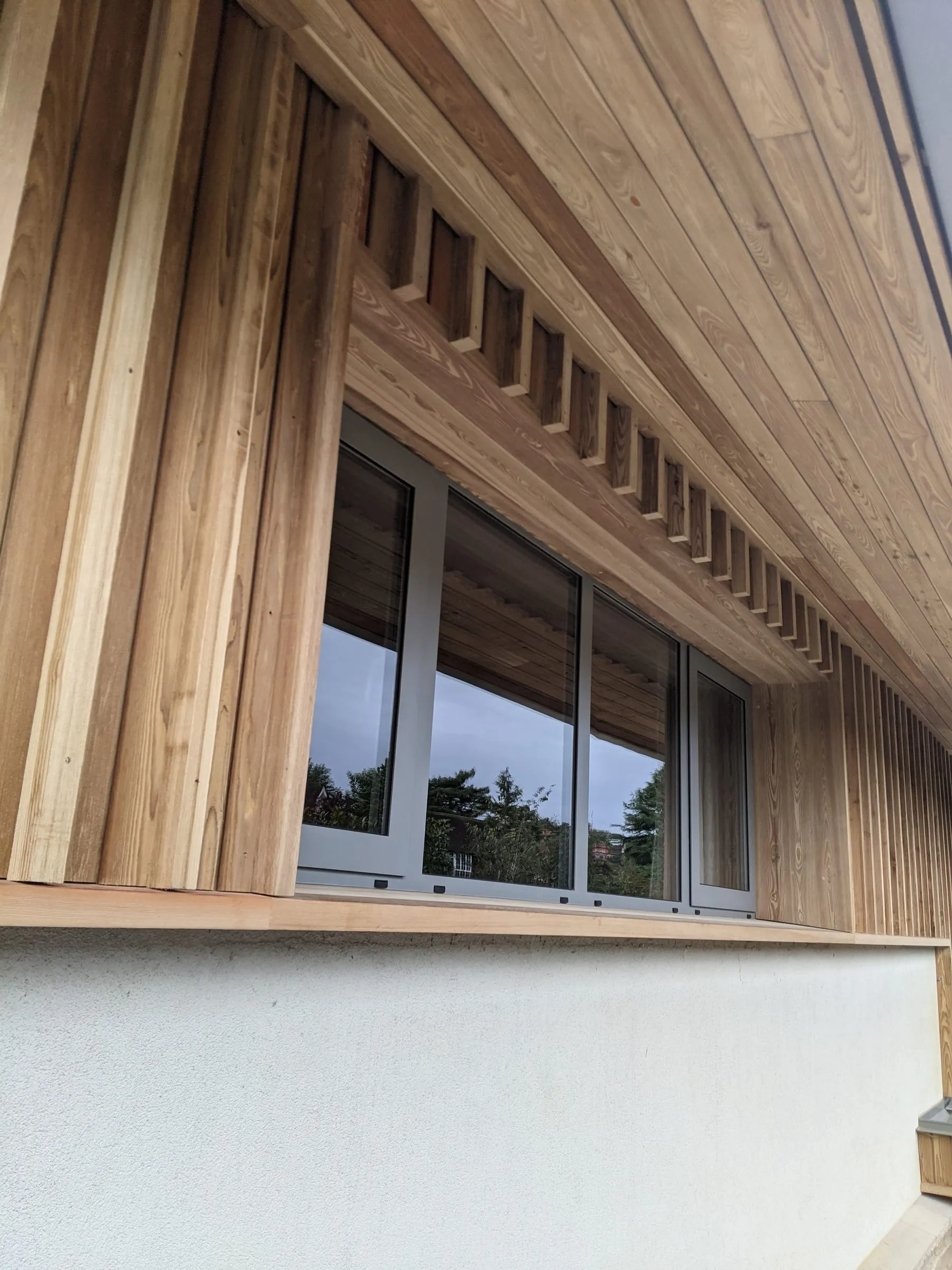 Larch cladding and soffit wrapping a first-floor window