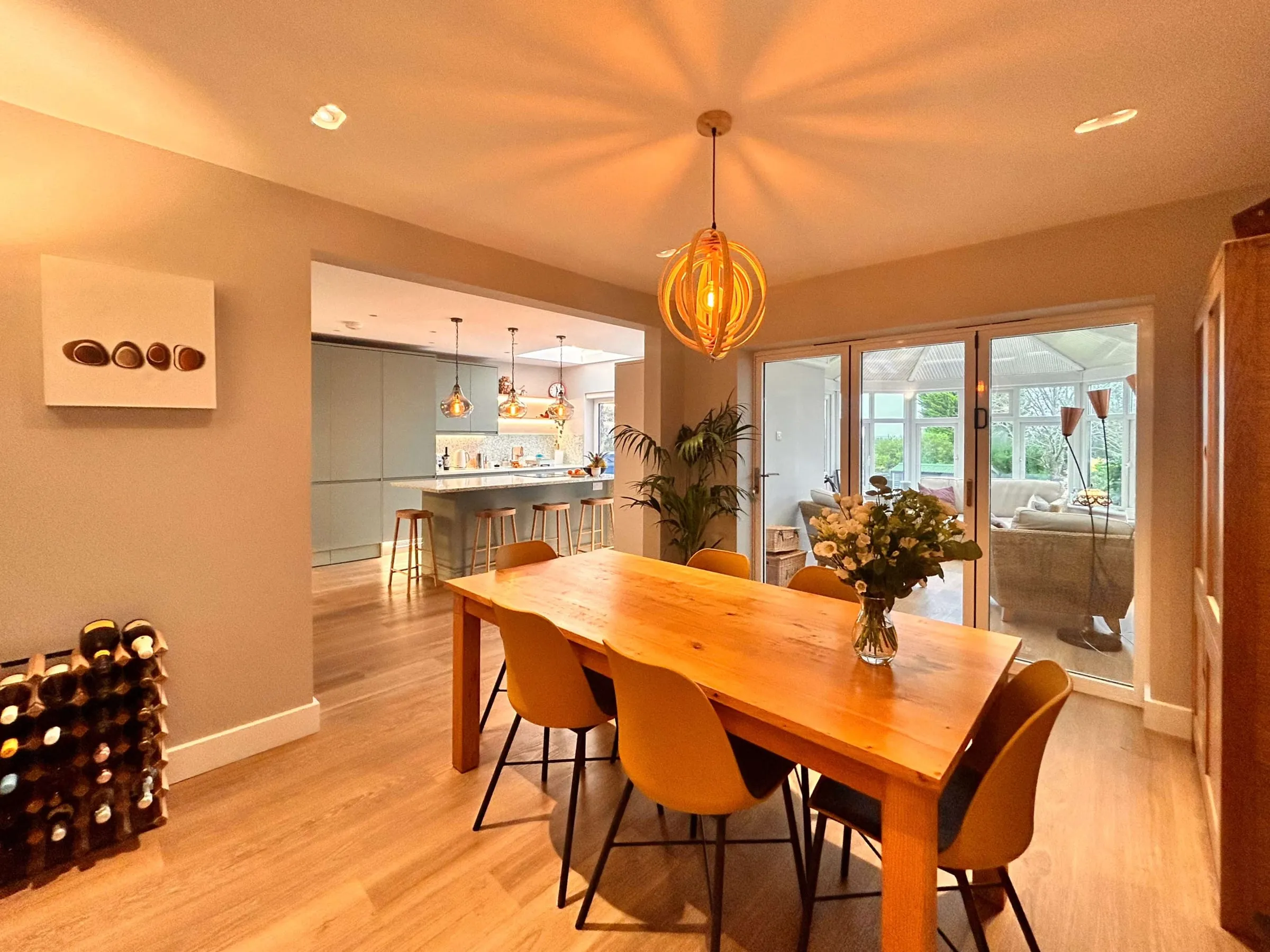 The dining end of the replanned Guildford kitchen, with a timber table, yellow chairs and doors to the garden