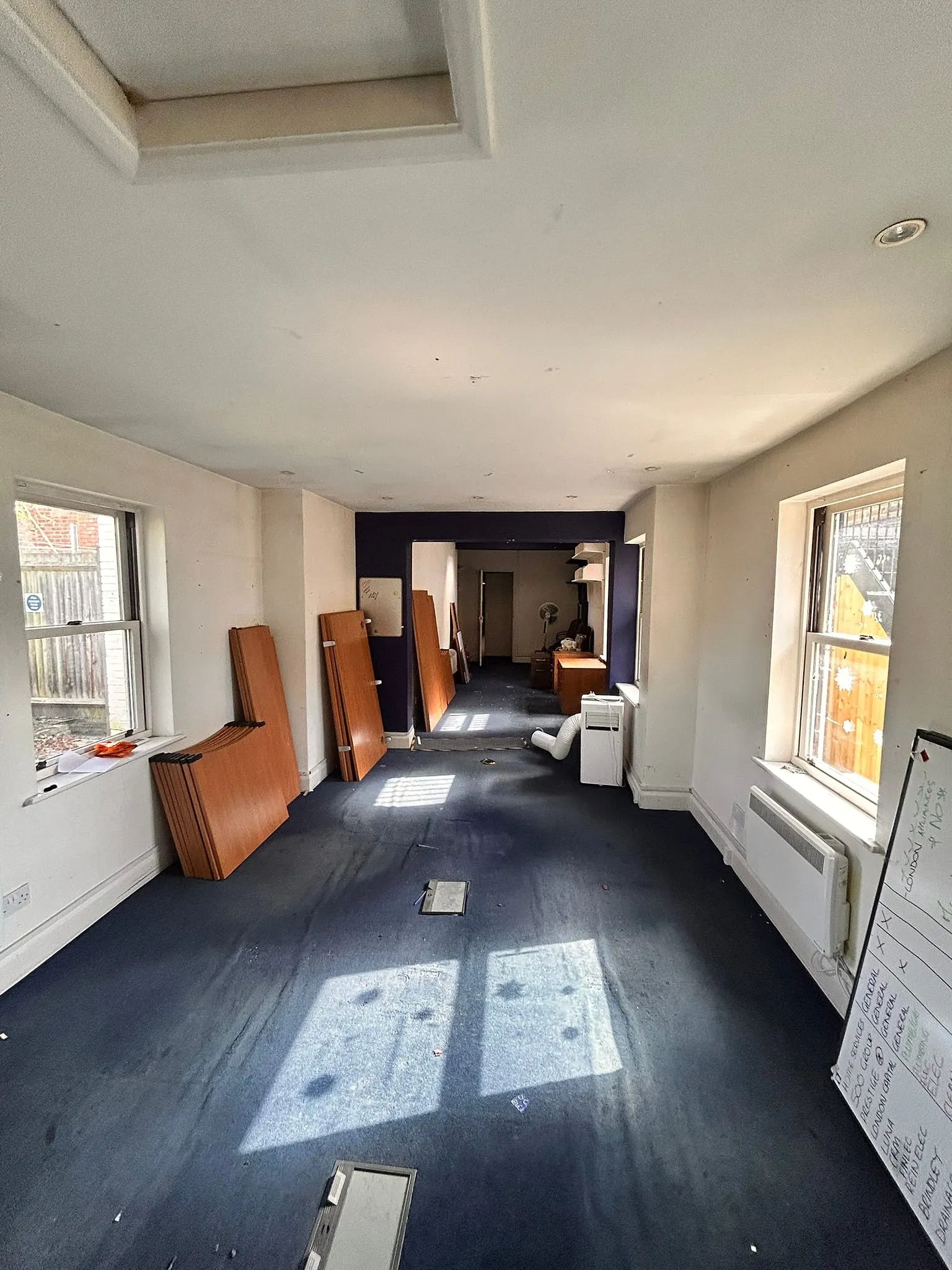 The ground-floor offices as we found them: a long room with suspended ceilings, blue carpet and old doors stacked against the wall