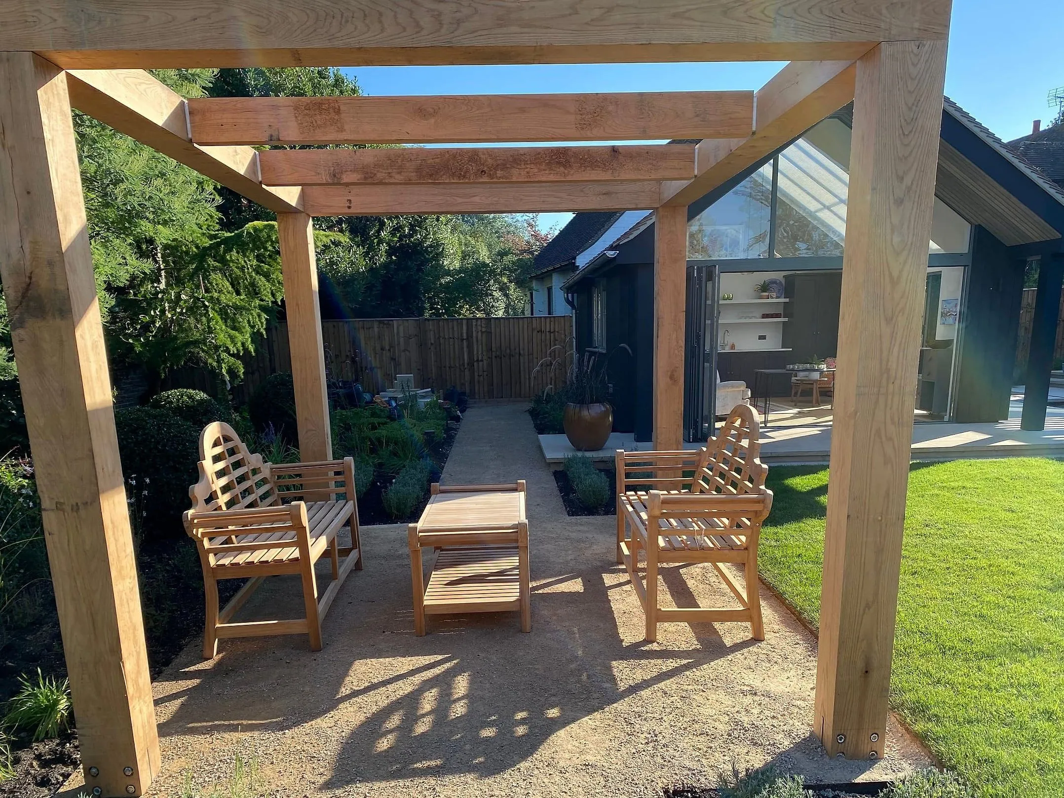 The oak pergola and seating on the lawn, with the garden room behind