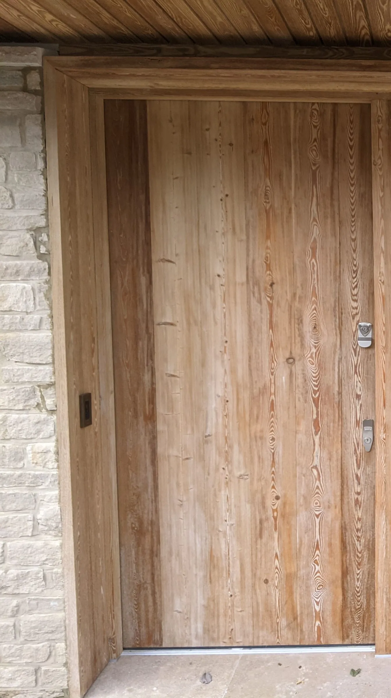 The oak front door set in the stone plinth beside the full-height glazing
