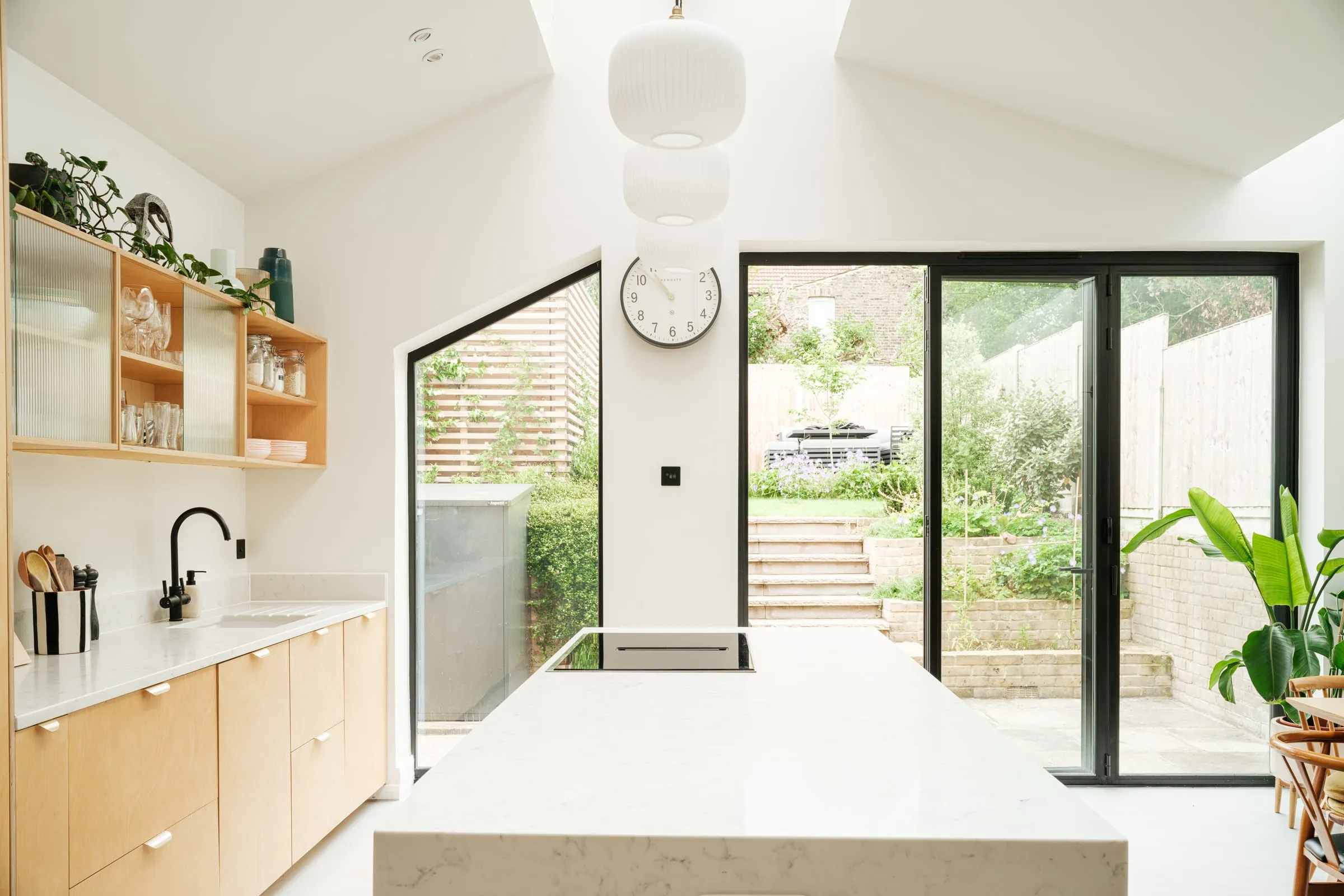 A bright kitchen extension in Walthamstow with tall glazed doors looking up to a terraced garden