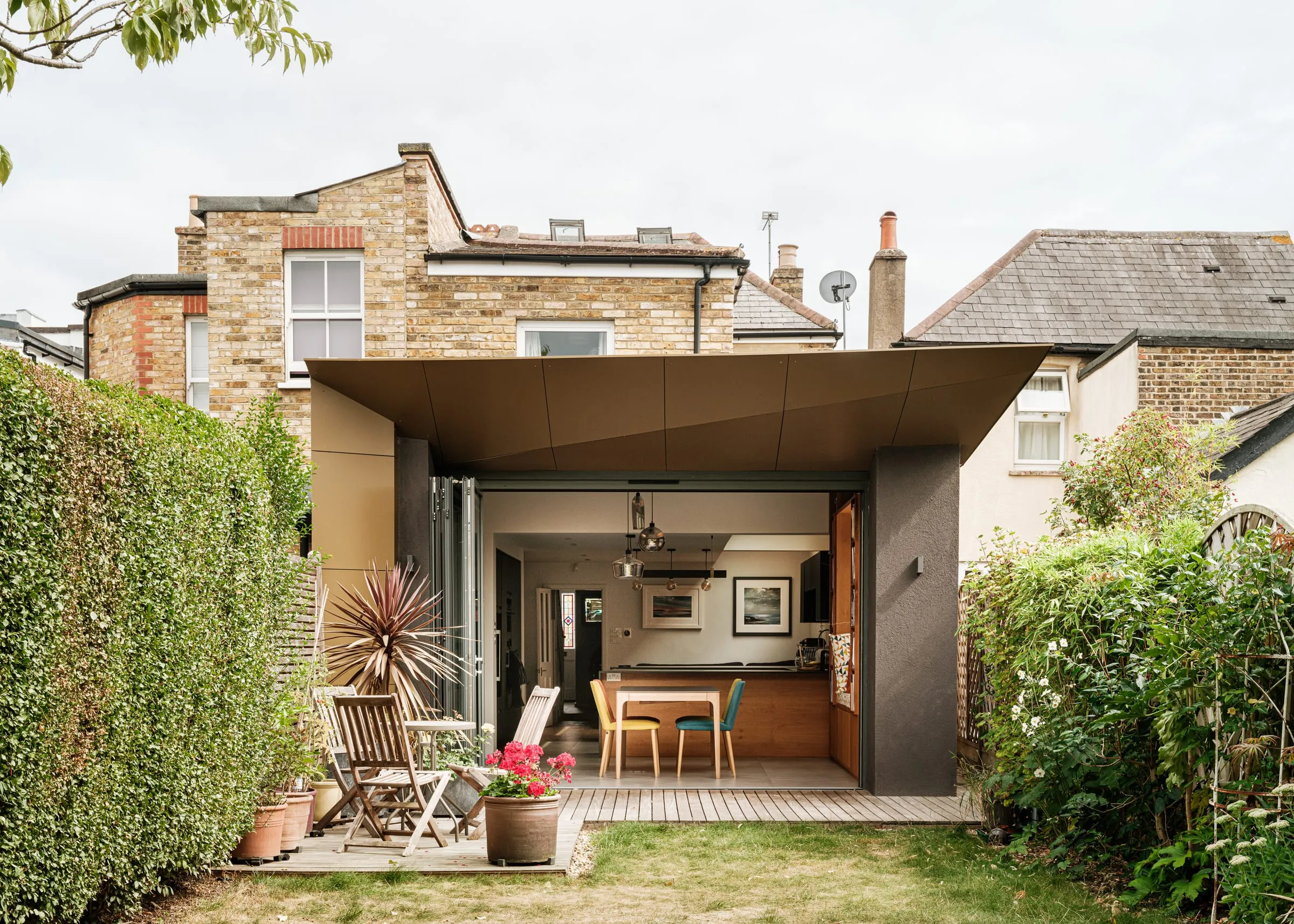 A timber-lined kitchen extension in East Molesey framed by dense garden planting