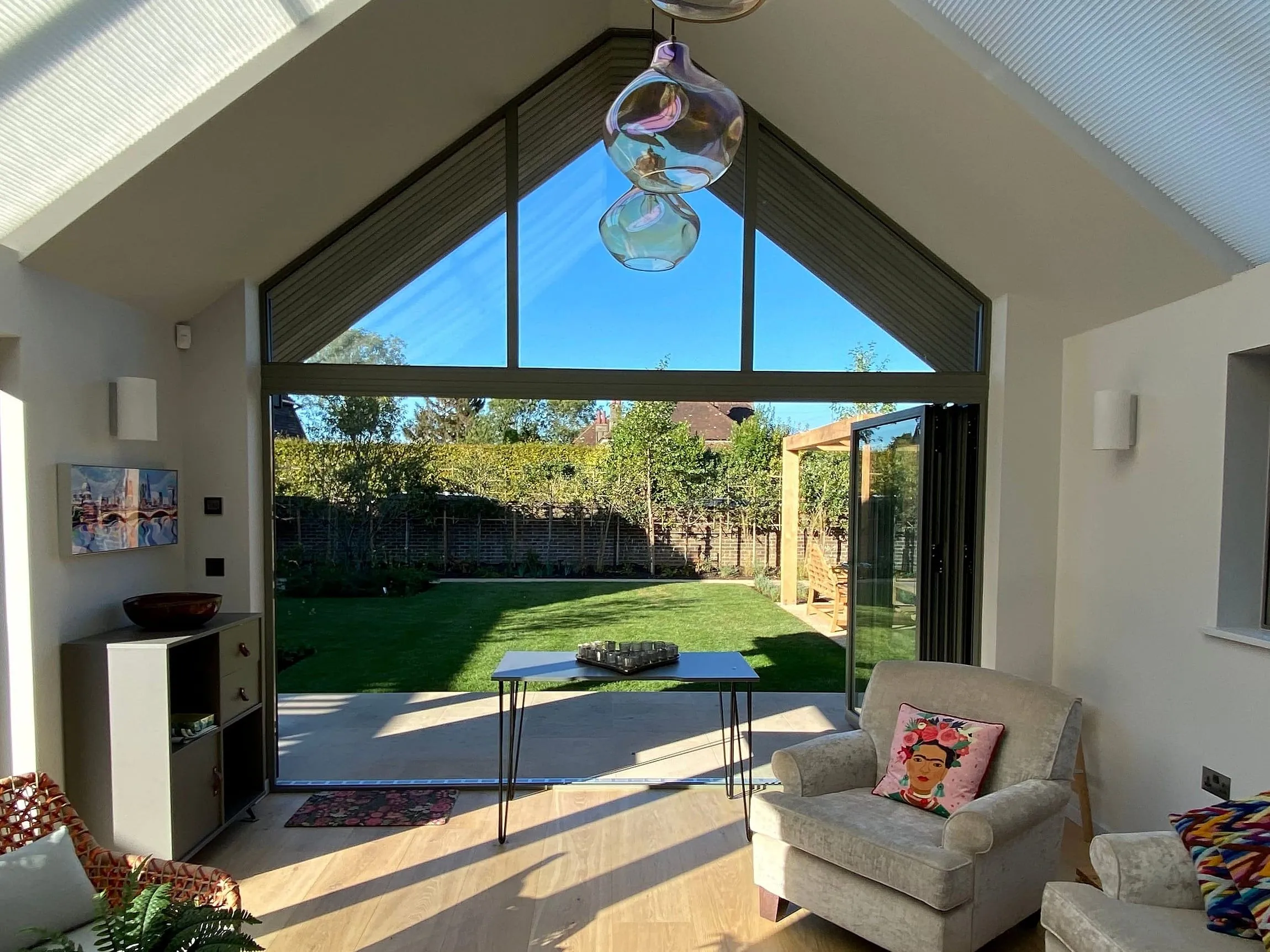Inside the garden room, looking out through the glazed gable to the lawn and pergola