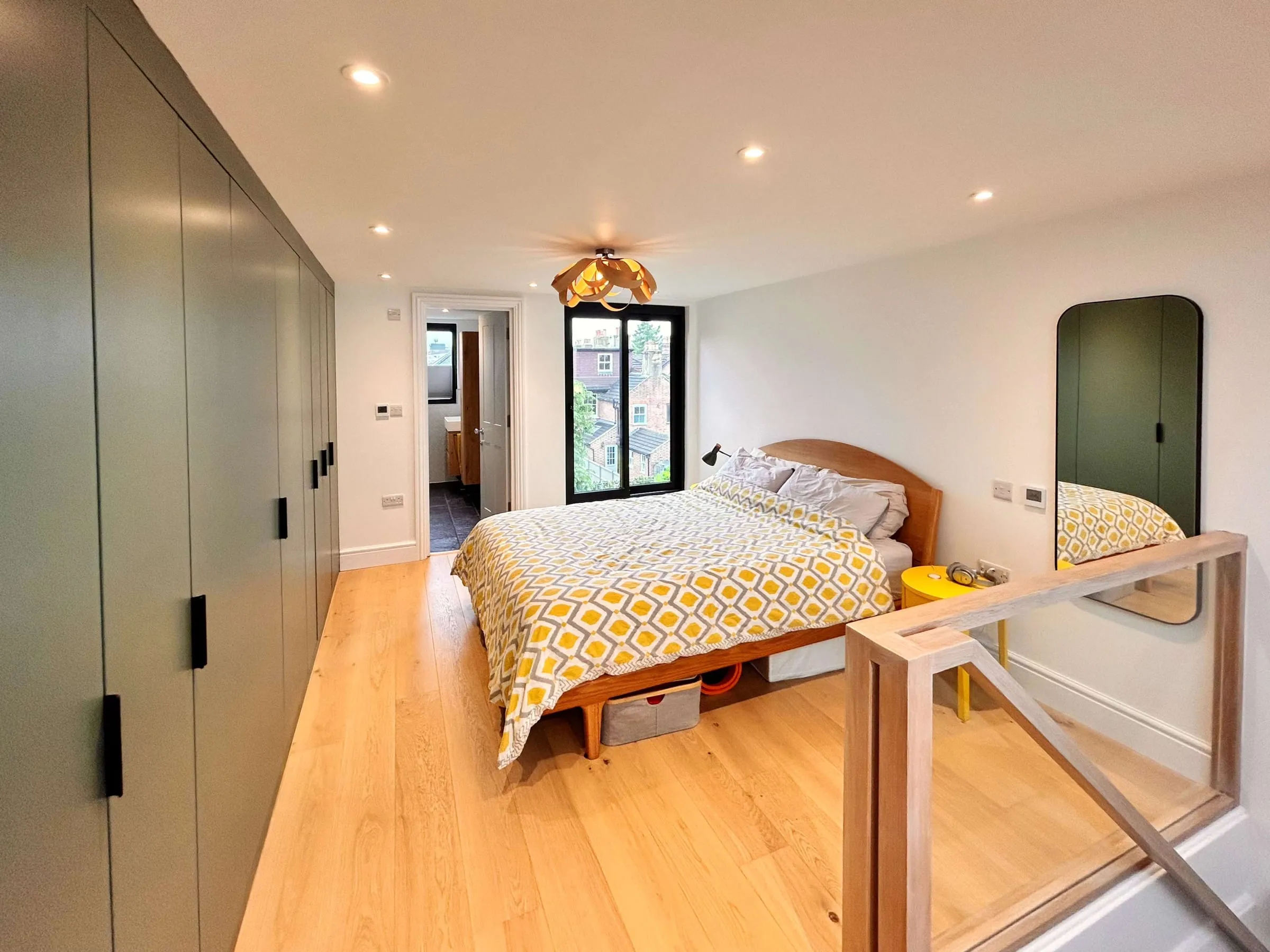 A loft bedroom with built-in wardrobes and a Juliet balcony in a converted townhouse roof