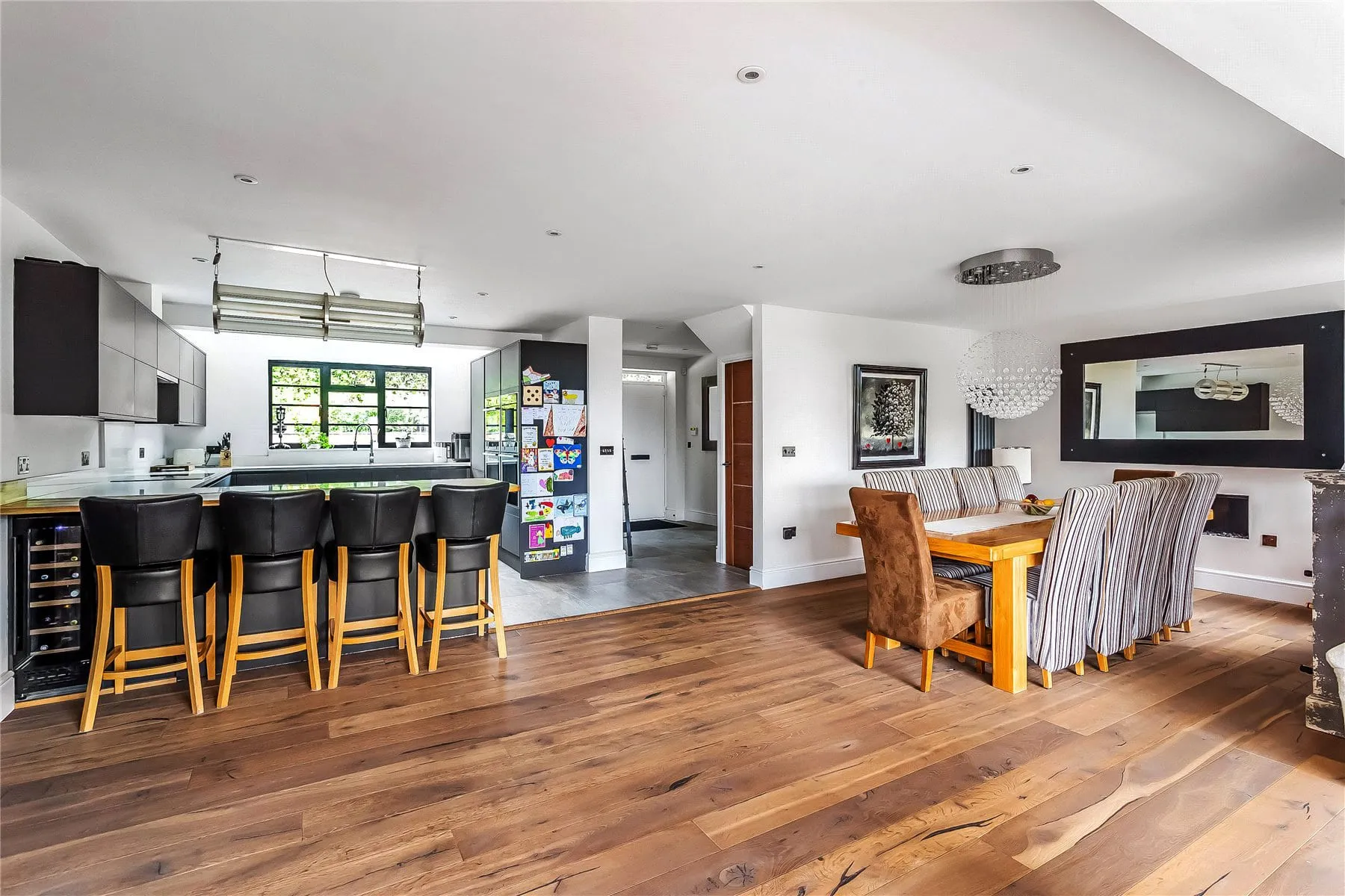 The open-plan kitchen and dining room in the Hook Heath house, with a breakfast bar, tall stools and a dining table beyond