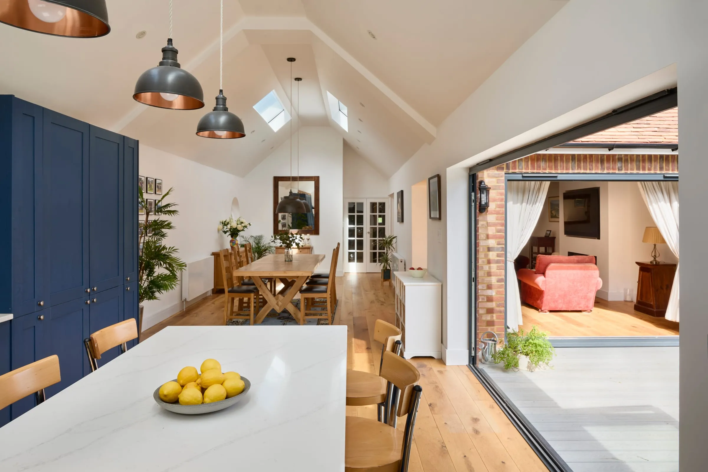Inside the Chobham bungalow: a vaulted kitchen with rooflights, opening through to the dining room and folding doors to the garden