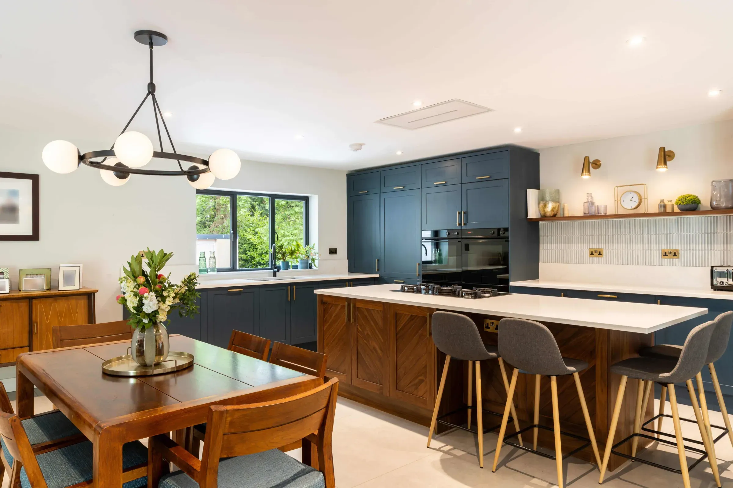 The kitchen in the Horsell bungalow, with dark blue units, a timber island and windows onto the garden