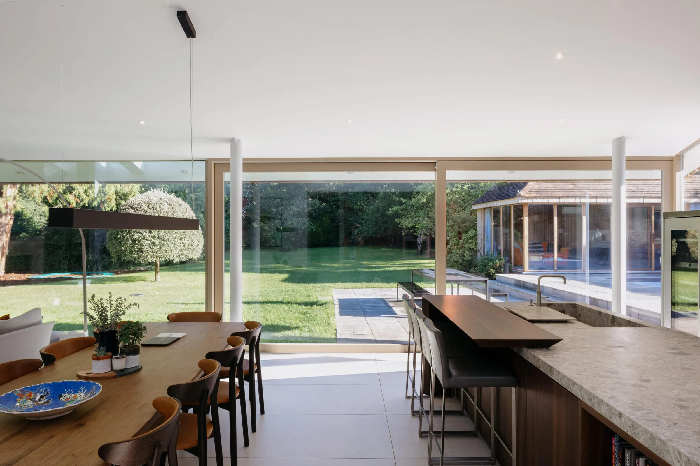 An open dining and kitchen space in the Woking bungalow, with full-height glass onto the garden