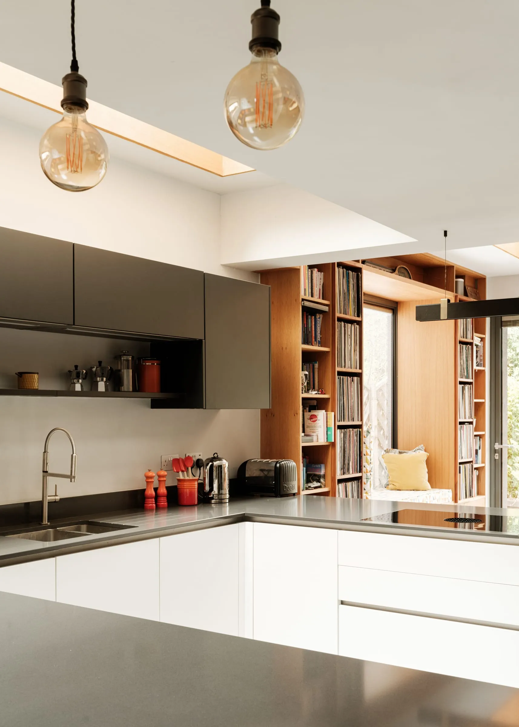 A matt black and white kitchen with an island and pendant lights, in the reworked East Molesey extension