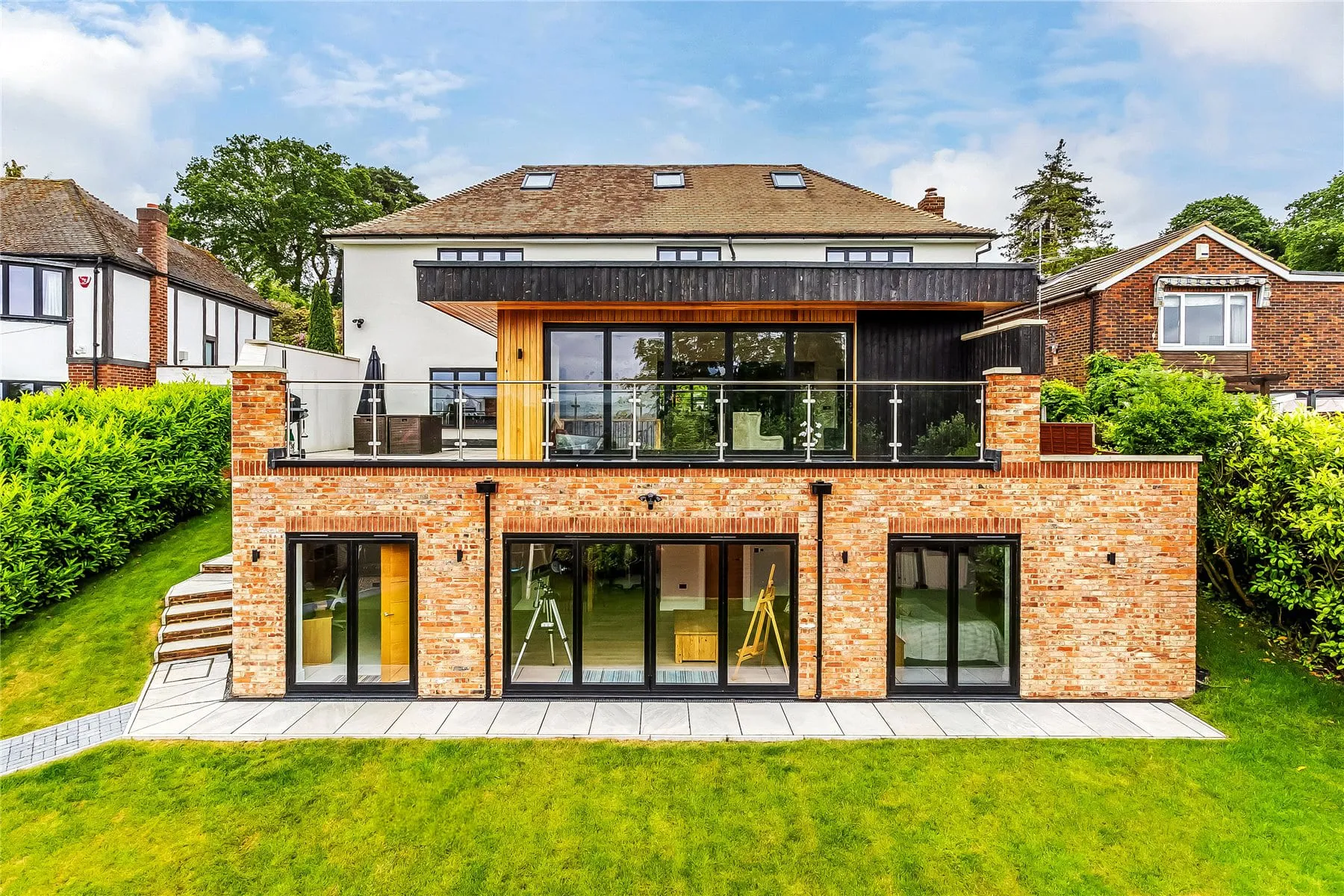 The garden side of a remodelled detached house in Hook Heath, Woking, with a new lower ground floor, glazed doors and a terrace