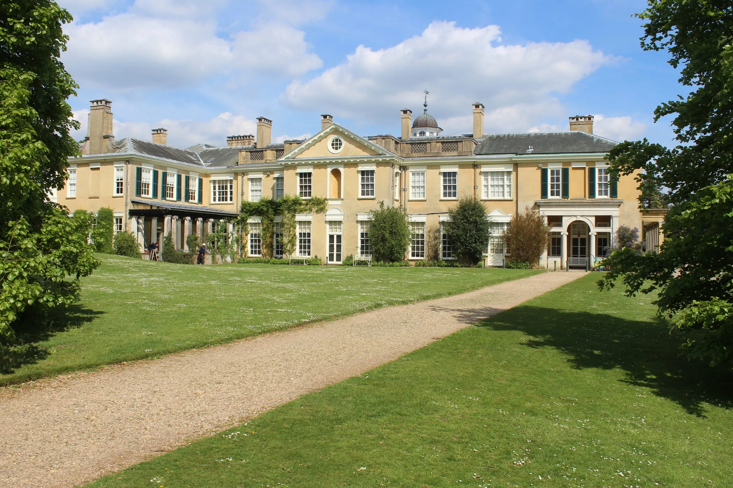 The west front of Polesden Lacey near Great Bookham, a yellow-rendered Regency house above a sweeping lawn